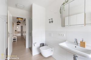 a white bathroom with a toilet and a sink at Pineapple Apartments Dresden Zwinger IX - 80 qm - 1x free parking - in Dresden