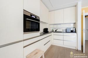 a white kitchen with white cabinets and a wooden stool at Pineapple Apartments Dresden Zwinger IX - 80 qm - 1x free parking - in Dresden