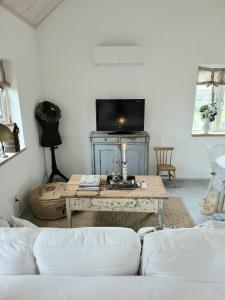 a living room with a table and a tv at Mysigt hus i liten by nära havet in Ystad