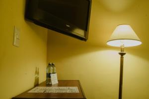 una lámpara sentada en una mesa junto a una TV en Hotel Posada San Agustin en Durango