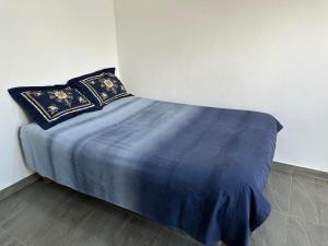 a bed with blue sheets and pillows in a room at Peace Hut in Nadi