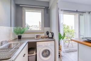 a kitchen with a sink and a washing machine at Zzzen aux portes de Paris avec Parking et Netflix in Vincennes