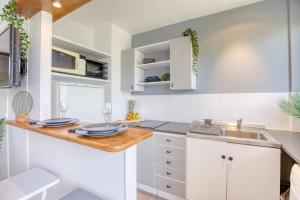 a kitchen with white cabinets and a wooden counter top at Zzzen aux portes de Paris avec Parking et Netflix in Vincennes