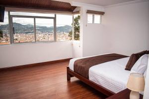 a bedroom with a bed and a large window at Hermosa casa con lujoso rooftop en Cuenca in Cuenca