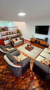 a living room with couches and a flat screen tv at Hermosa casa con lujoso rooftop en Cuenca in Cuenca
