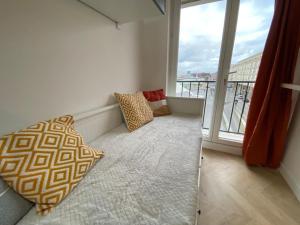 a balcony with a bed and a large window at L'Escale Appartements et Suites en bord de Mer in Le Havre