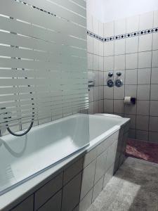 eine weiße Badewanne in einem weiß gefliesten Bad in der Unterkunft Charmante Ferienwohnung in Dresden Striesen - Frau Pie Appartement in Dresden