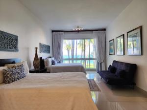 a bedroom with two beds and a couch and a window at SEAWINDS CABARETE Front beach Condo in Cabarete