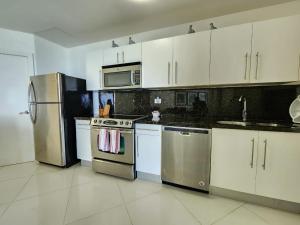 una cucina con armadietti bianchi ed elettrodomestici in acciaio inossidabile di SEAWINDS CABARETE Front beach Condo a Cabarete