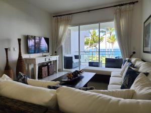 un soggiorno con divani bianchi e TV di SEAWINDS CABARETE Front beach Condo a Cabarete