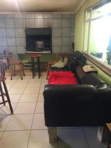 sala de estar con sofá de cuero negro y mesa en Vukaphi Farm, en Cleland