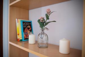 un jarrón con flores y dos velas en un estante en Bonito piso en San Ildefonso - Centro, en Jaén