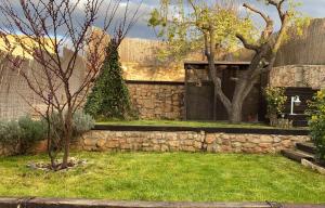 a stone house with a stone wall and a yard at Apartamentos Ohana in Jadraque