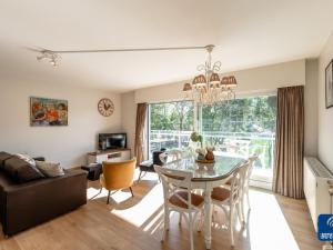 uma sala de jantar e sala de estar com mesa e cadeiras em Parkhouse B201 cosy apartment in De Haan em De Haan