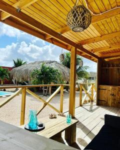 a patio with a table and a straw roof at Bella Blue Bonaire 2 in Kralendijk