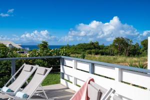 twee stoelen op een terras met de oceaan op de achtergrond bij Villa Paruline in Grand-Bourg