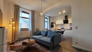 a living room with a blue couch and a kitchen at YourFavoriteBed Designerapartments Zwickau Zentrum in Zwickau