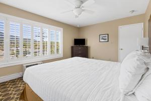 a bedroom with a large white bed and windows at Marin Suites Hotel in Corte Madera