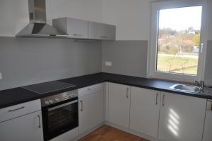 a kitchen with white cabinets and a sink and a window at Sonnige Neubauwohnung - Gratwein in Kugelberg