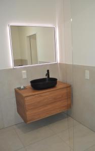 ein Bad mit einem schwarzen Waschbecken und einem Spiegel in der Unterkunft Sonnige Neubauwohnung - Gratwein in Kugelberg