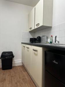 a kitchen with white cabinets and a black dishwasher at Cosy entire apartment super king bed near town center in Colchester
