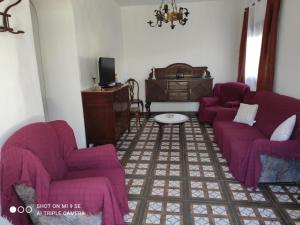 una sala de estar con sofás morados y una mesa. en Cortijo Ferre, a los pies del castillo la Atalaya de Nijar en Níjar