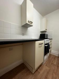 a kitchen with white cabinets and a black counter top at Cosy entire apartment super king bed near town center in Colchester