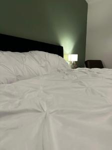 a large white bed in a bedroom with a lamp at Cosy entire apartment super king bed near town center in Colchester