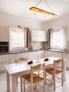 - une cuisine avec une table et des chaises blanches dans l'établissement Villas Scirocco, à Fira