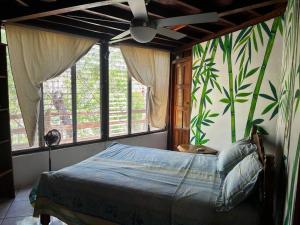 a bedroom with a bed in a room with windows at Jungle Farm, Digital Detox Cottage in Nicaragua in La Esperanza