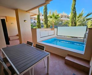 un patio con piscina, mesa y mesa en Private Apartment & Pool - El Oasis Golf Resort - Fuente del Alamo, en Murcia