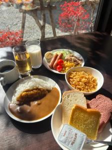 une table avec des assiettes de nourriture, du pain et du lait dans l'établissement Hotel Rosso Karuizawa, à Karuizawa