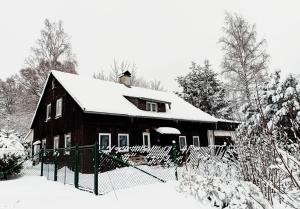 a wooden house with snow on the roof at Chata Koza in Bublava