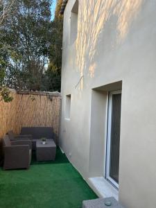 een patio met een bank, een tafel en een raam bij Sandspa logement avec jacuzzi in Orange