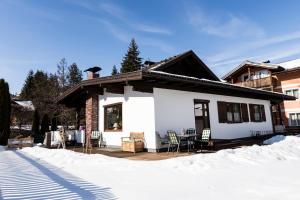 une maison blanche avec une terrasse dans la neige dans l'établissement Bungalow Nr. 33, à Altenmarkt im Pongau