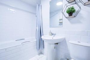 a white bathroom with a sink and a tub at Grand and Stylish 3BR Apartment in Greater London in London