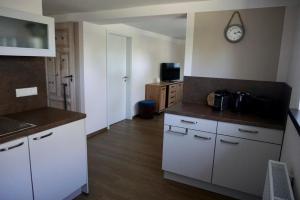 Una cocina con gabinetes blancos y un reloj en la pared. en FeWo herein SPAZIERT, en Schmiedefeld am Rennsteig 5 fotos más