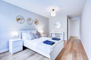 a white bedroom with a white bed and two mirrors at Grand and Stylish 3BR Apartment in Greater London in London