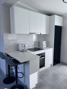 uma cozinha com armários brancos e um frigorífico preto em Cosea Langebaan em Langebaan