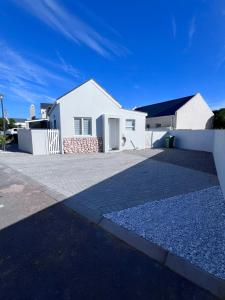 uma casa branca com uma cerca e uma entrada em Cosea Langebaan em Langebaan