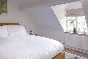 1 dormitorio con cama blanca y ventana en Stunning 2BD in the Heart of Malmesbury!, en Malmesbury