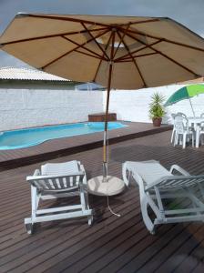 una sombrilla y sillas en una terraza con piscina en Moradas dos Sonho, en Palhoça