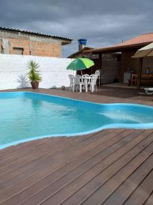 una piscina con una terraza de madera y una sombrilla en Moradas dos Sonho, en Palhoça