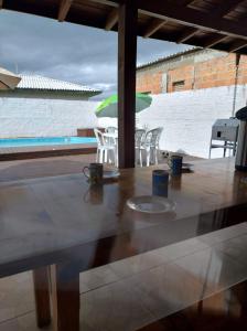 una mesa con sillas, una sombrilla y una piscina en Moradas dos Sonho, en Palhoça