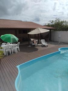 una piscina con sillas y sombrillas junto a una casa en Moradas dos Sonho, en Palhoça