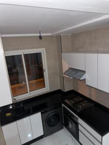 eine kleine Küche mit einem Herd und einem Fenster in der Unterkunft Appartement vue sur mer - 3 chambres - garage privé in Al Hoceïma