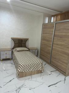 Schlafzimmer mit einem Bett mit einem großen Kopfteil aus Holz in der Unterkunft Appartement vue sur mer - 3 chambres - garage privé in Al Hoceïma