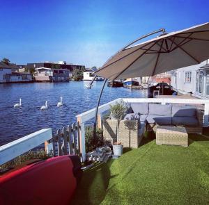 a patio with an umbrella next to a body of water at Amster Houseboat Bed without Breakfast in Amsterdam