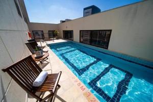 a large swimming pool with two chairs and a table at FLAT in DENTRO DO HOTEL 4 ESTRELAS - ACOMODA ATÉ 4 PESSOAS RUA DIOGO MOREIRA 247 , CORAÇÃO DA FARIA LIMA - ÓTIMA LOCALIZAÇÃO, e CONFORTO in São Paulo