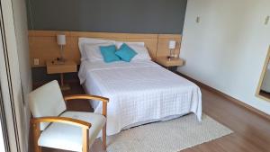 um quarto com uma cama com almofadas azuis e uma cadeira em Atlântica Hotel 5 estrelas - Coração da Faria Lima em São Paulo